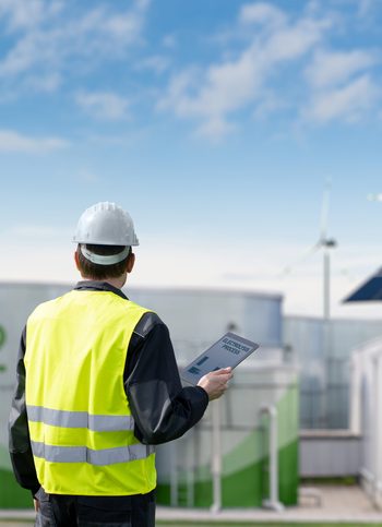 Engineer with tablet computer on a background of Green Hydrogen factory