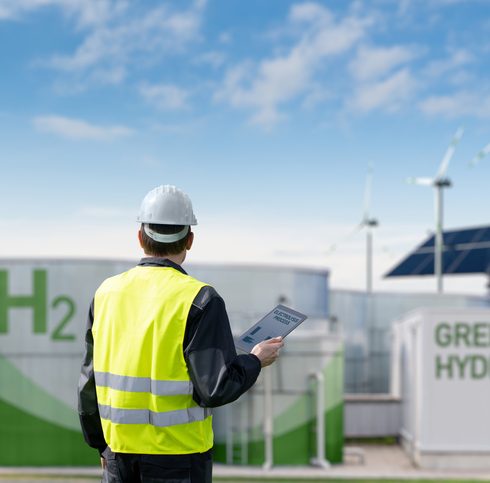 Engineer with tablet computer on a background of Green Hydrogen factory